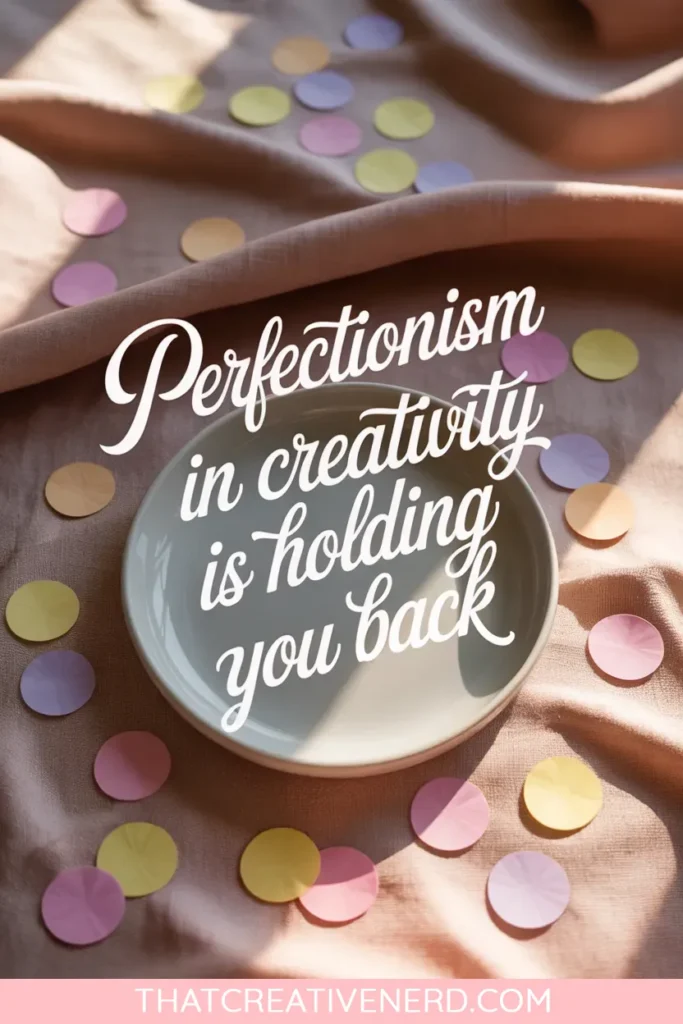 A ceramic plate centered on a blush fabric background, surrounded by scattered pastel confetti. The image features overlaid script text saying, "Perfectionism in creativity is holding you back."